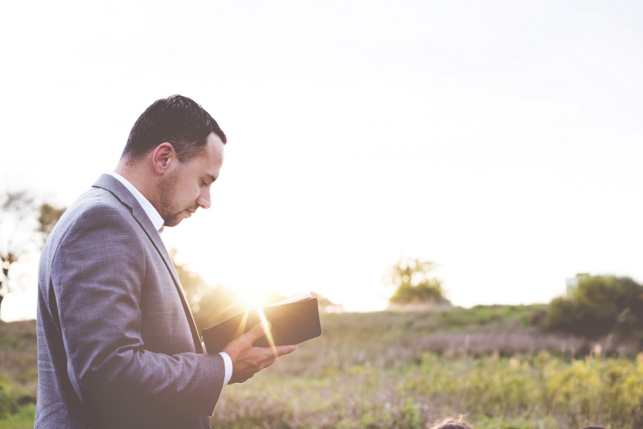 A man opening up the Bible as the sun rises.