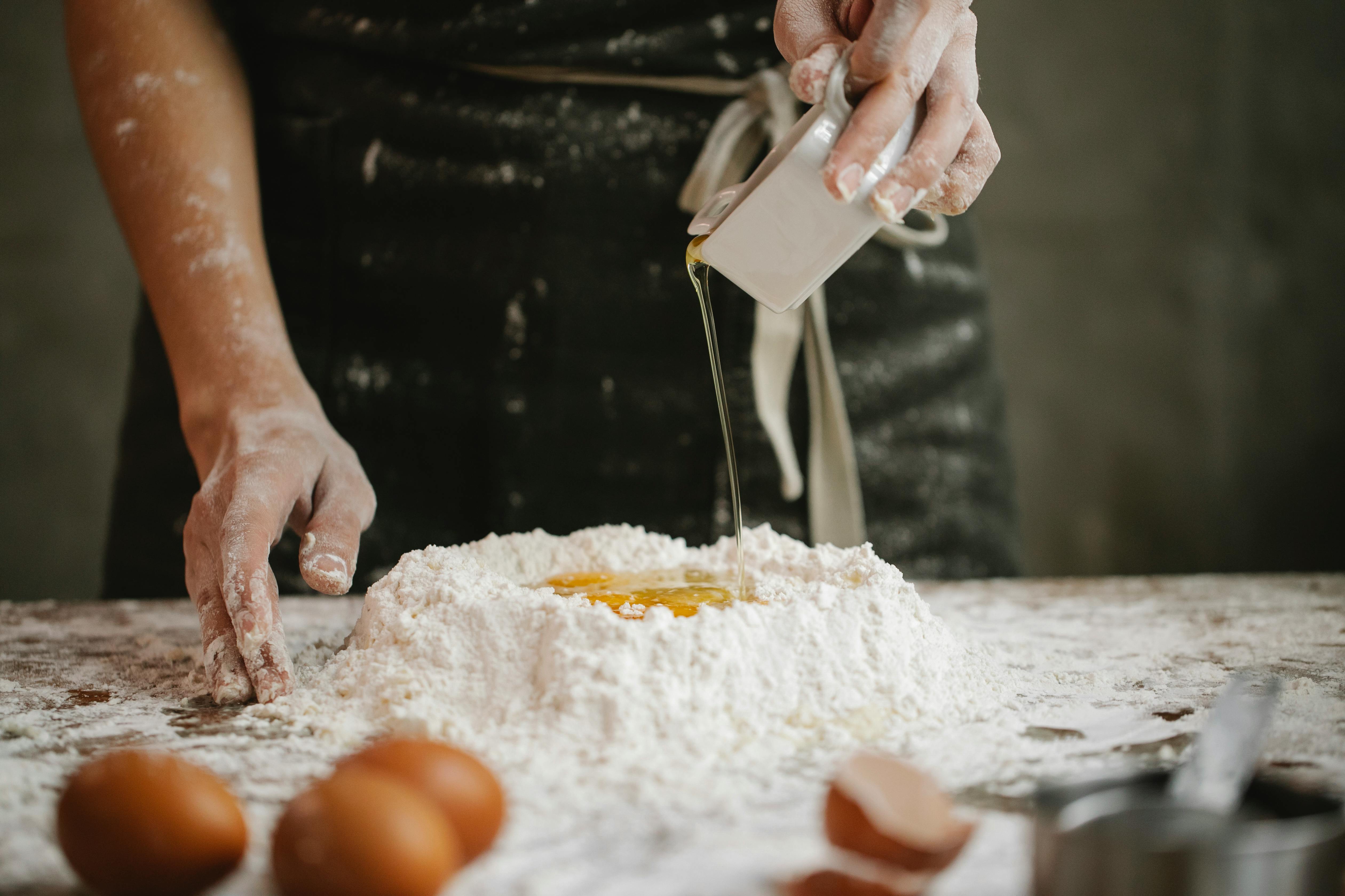 baker pouring egg mixture into prepared flour mound baker pouring egg mixture into prepared flour mound